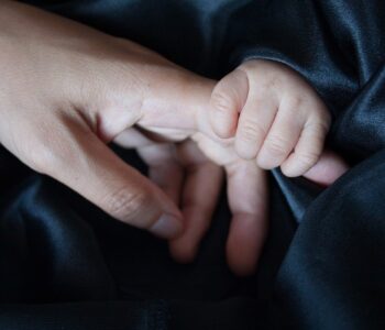 Photo of infant holding parent's finger
